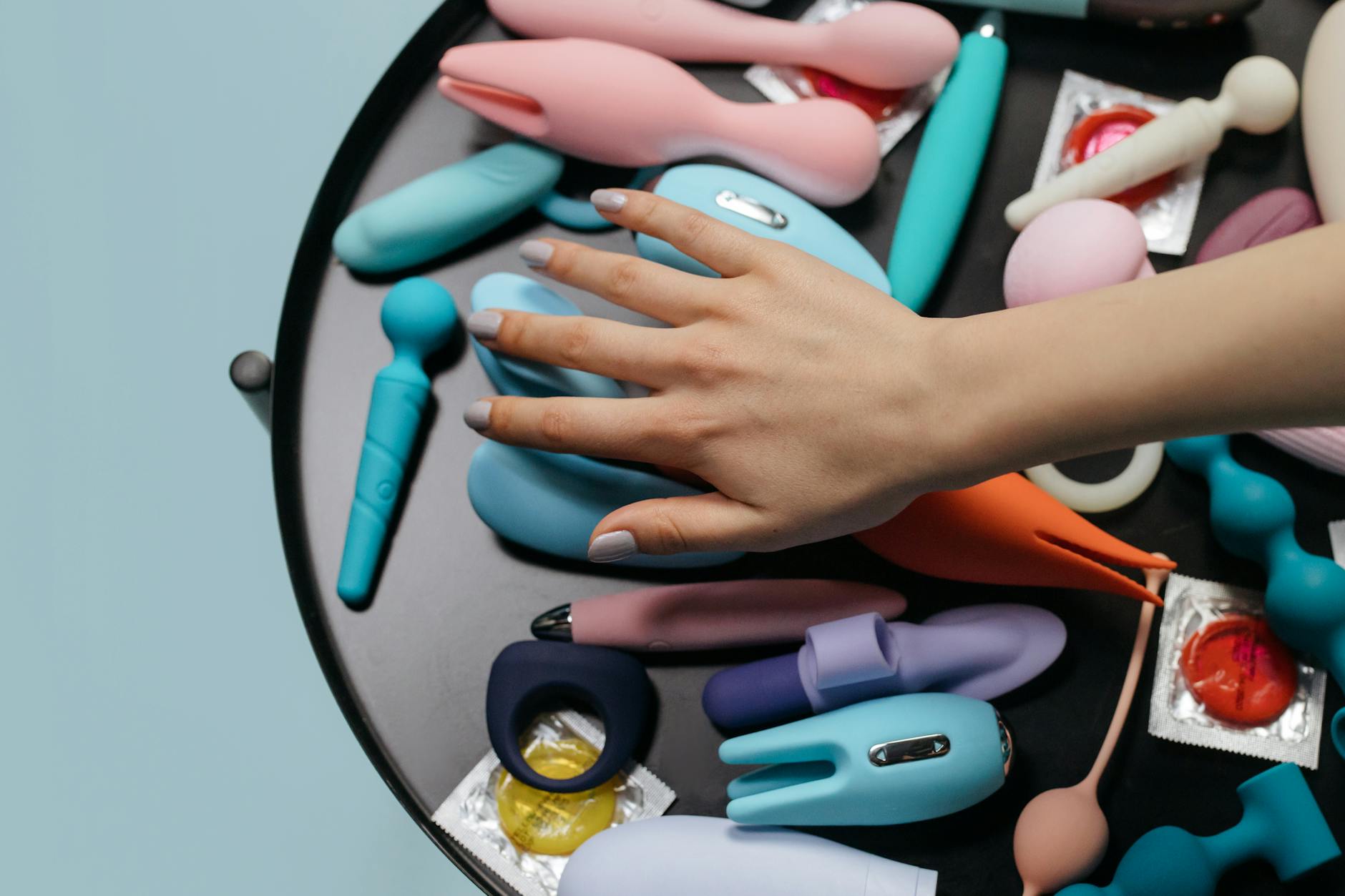 Woman holding blue and pink silicone vibrators in a contemplative moment of self-care and reconnection