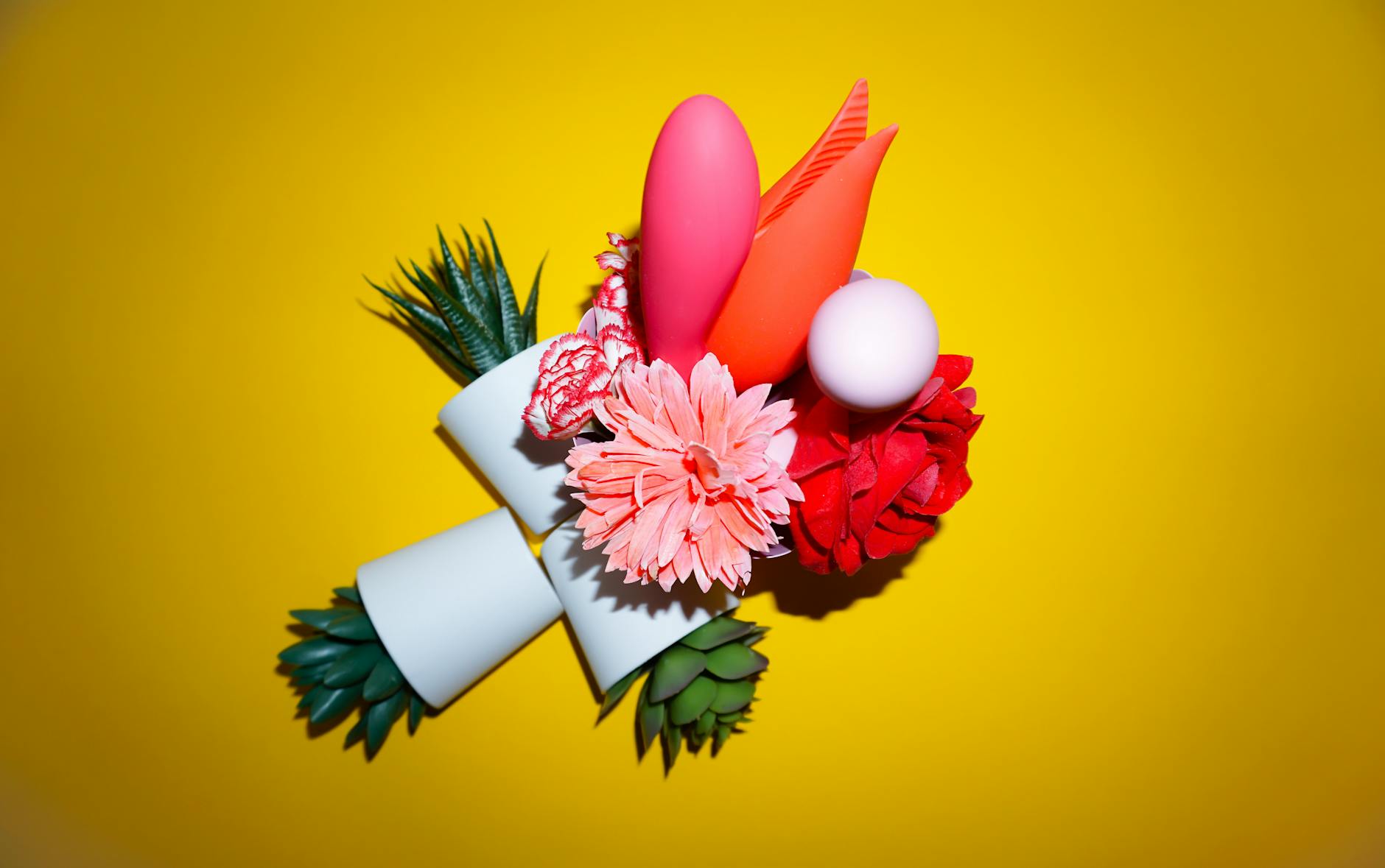 Colorful vibrators and adult toys arranged on a bright yellow background