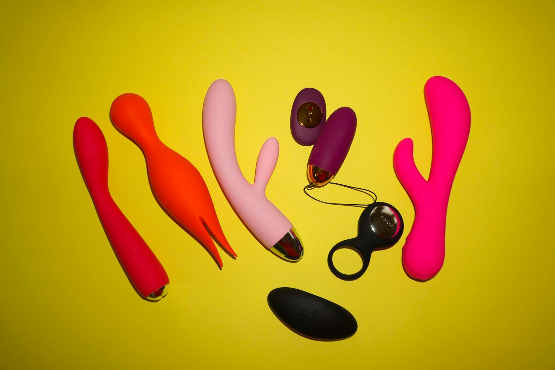 Hand holding a blue silicone vibrator against a purple background